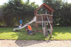A playground with a slide and a wooden playhouse. - Country holiday at Birkenhof (Kittlitz)
