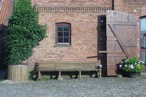 A brick building with a wooden bench and a large wooden gate. - Country holiday at Birkenhof (Kittlitz)