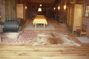 A rustic interior with a long dining table, wooden flooring, and a fur rug. - Country holiday at Birkenhof (Kittlitz)