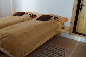 A double bed with a wooden headboard, two bedside tables with lamps, a striped rug, and a wooden wall decoration. - Country holiday at Birkenhof (Kittlitz)