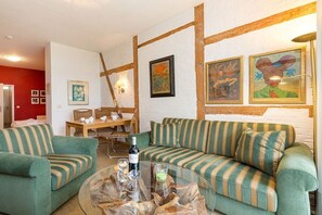 A living room with striped sofas, a glass coffee table, and framed artwork on the wall. - Holiday apartment in Binz with swimming pool (Binz)