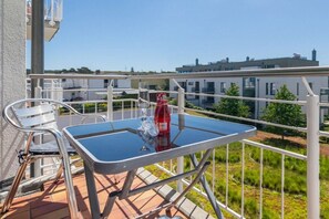 Ein Balkon mit Tisch, Stühlen, einer Flasche und Gläsern.
