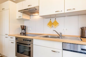 A modern kitchen with white cabinetry, a double sink, a coffee maker, and a dishwasher. - First floor, Bel Vital Residence (Binz)