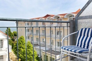 A balcony with a metal railing, a striped chair, and a view of a multi-story building with balconies. - Holiday apartment in Binz with swimming pool (Binz)