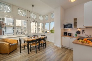 A modern kitchen with a dining area, large windows, and a view of the outside. - Sea greetings at Villa Agnes (Binz)