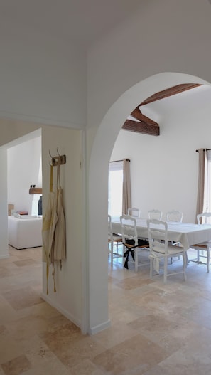 A spacious dining area with a white table and chairs, an arched ceiling, and a view through an open doorway. - Maison Olivette: Provençal villa with a private pool, 6 bedrooms, and olive trees (Flayosc)