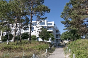 A pathway leading to a modern multi-story building surrounded by trees. - at Villa Vogue, Baltic Sea Dream (Binz)