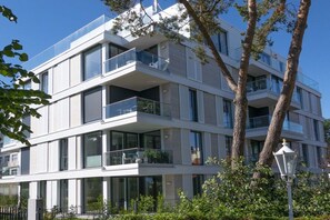 Un immeuble à plusieurs étages, doté de balcons, de grandes fenêtres et surplombant un ciel dégagé.