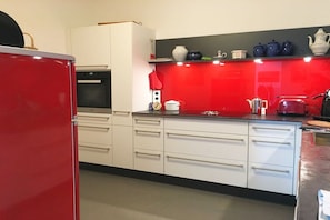 Eine Küche mit weißen Schränken, einem roten Kühlschrank und einer roten Spritzschutzwand.