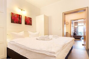 Ein Hotelzimmer mit einem großen Bett, zwei Wandleuchten und Blick auf den Balkon durch eine geöffnete Tür.