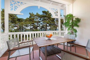 A covered outdoor seating area with a table and chairs, a potted plant, and a view of trees. - "Bella Vista" at Villa Seeadler (Binz)