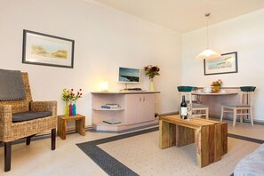 A furnished living room with a sofa, a small table, a cabinet, and a dining area with chairs and a table. - "Bella Vista" at Villa Seeadler (Binz)