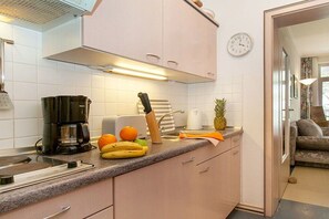 Eine Küche mit Kaffeemaschine, Obst und einer Uhr an der Wand.