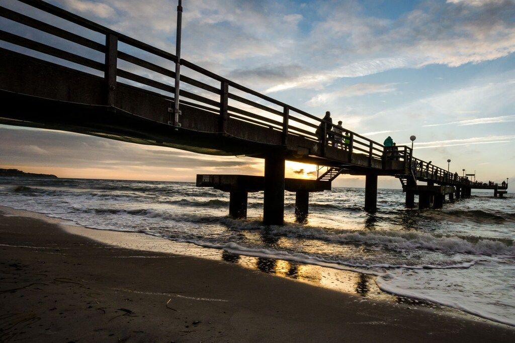 A pier extending into the sea with a sunset in the background.