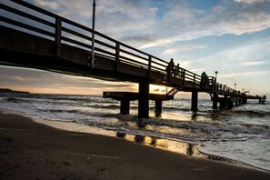 Eine Steg, der sich ins Meer erstreckt, mit einem Sonnenuntergang im Hintergrund.