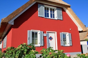 A red building with white shutters, a number '58' on the door, and a small European flag. - Thatched House "Seagull Emma" (Zierow)