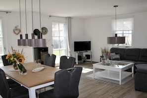 Ein modernes Wohnzimmer mit Essbereich, einem Flachbildfernseher und einem Kamin.