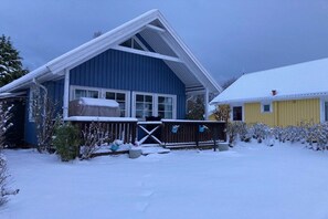 Een huis met twee verdiepingen, met een blauwe buitenkant en een aangrenzend geel gebouw, beide bedekt met sneeuw.