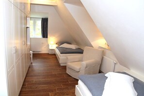 A compact room with a bed, a chair, and a wardrobe. - "Friesenhaus Hensen" (Nebel)