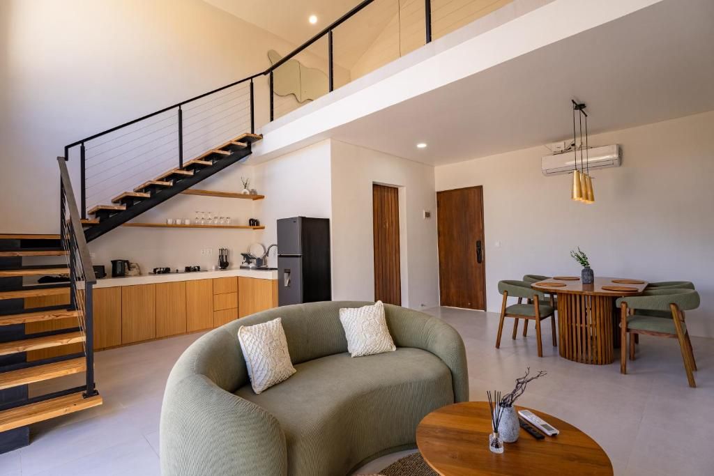Un espacio habitable moderno con una escalera, un sofá, una mesa de comedor y una zona de cocina.