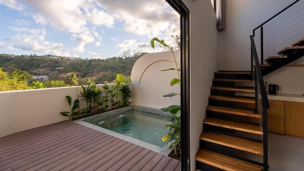 A modern interior with a wooden staircase, a small pool, and a view of a hilly landscape. - Eala Estate (Pujut, Central Lombok Regency)