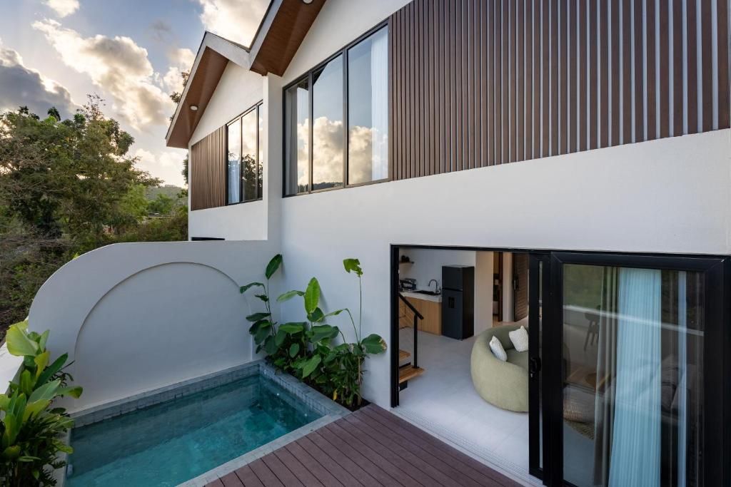 Een modern huis met twee verdiepingen, een zwembad, grote ramen en een balkon.