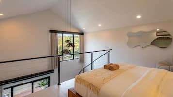 Un dormitorio moderno con una cama grande, vistas a zonas verdes a través de una ventana, una escalera y un espejo de pared original.