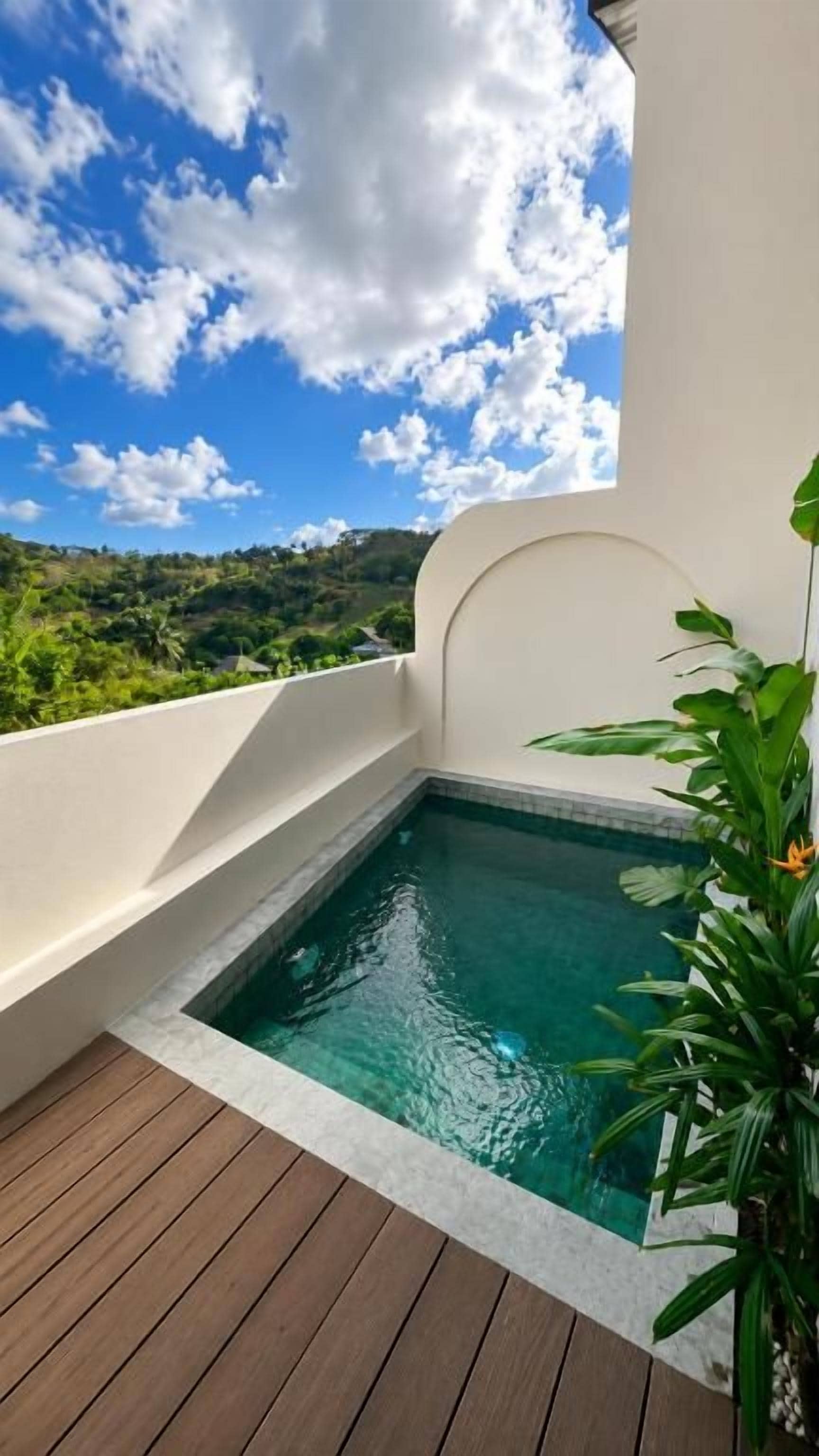 Piscina no terraço com vista ampla para uma paisagem verde e céu azul.