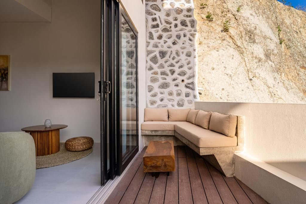 Ein modernes Interieur mit einer Glastür, die auf einen Balkon führt, ein beiges Sofa und ein Holztisch.