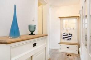 A hallway with a wooden bench, a hanging bag, and a pair of shoes on the floor. - Villa Poseidon 02 - East Wind (Ostseebad Binz)
