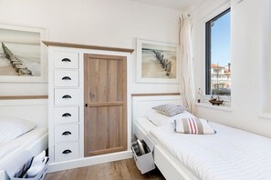 A bedroom with a bed, a wardrobe, and a window with a view. - Villa Poseidon 02 - East Wind (Ostseebad Binz)