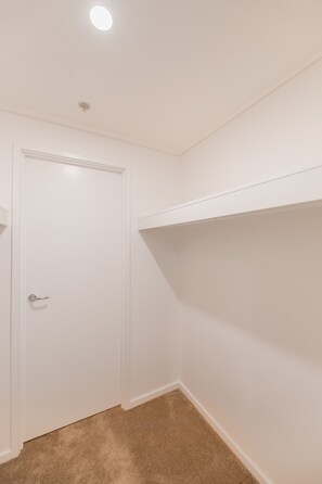 Ein Zimmer mit einer weißen Tür, einer Deckenleuchte und einem Teppichboden.
