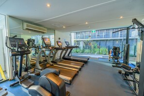 Et fitnesscenter med løbebånd, crosstrainere og styrkeudstyr.