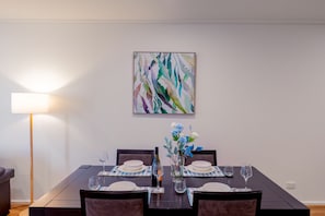 Ein Essbereich mit einem Tisch für vier Personen, einer Blumenvase und einem Bild an der Wand.
