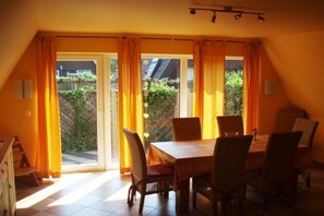 Ein Essbereich mit Tisch und Stühlen, eine Schiebetür zu einem Garten und eine geneigte Decke.