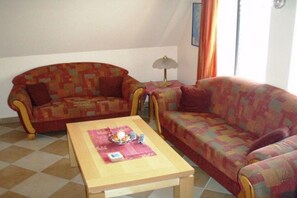 Ein Wohnzimmer mit zwei Sofas, einem Couchtisch und einer Lampe.