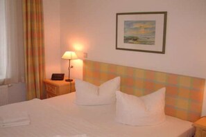 Ein Hotelzimmer mit Bett, Nachttisch, Lampe und einem gerahmten Bild an der Wand.