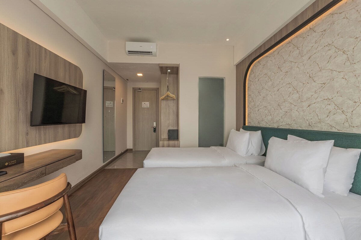 A hotel room with a bed, a TV, a desk, and a mirror.