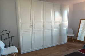 Ett rum med en stor vit garderob, en vit stol och ett litet bord.