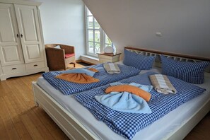 A bedroom with a bed, a wardrobe, a chair, and a window. - Holiday home in Usedom with 4 bedrooms (Zinnowitz)