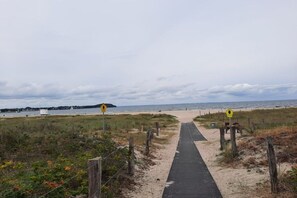 A pathway leading to a beach with a wooden fence on one side and a signpost in the distance. - Holiday home in Travemünde with Wi-Fi (Travemünde)