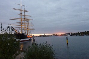 A large sailing ship docked at a harbor with a city skyline in the background. - Holiday home in Travemünde with Wi-Fi (Travemünde)