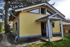 A yellow single-story house with a covered porch, a visible door, and a window. - Holiday home in Travemünde with Wi-Fi (Travemünde)