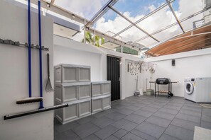 Ein Waschbereich mit Waschmaschine, Wäscheständer und Grill.