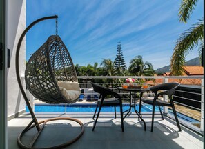 Ein Balkon mit einer Hängematte, einem Tisch mit Stühlen und einem Pool.