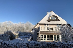 A house with a steeply pitched roof, a balcony with a railing, and a large window. - Holiday home with 1 bedroom (Groß Schwansee)