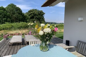 Eine Terrasse im Freien mit Tisch, Stühlen, einem Blumenstrauß und einem Lautsprecher.