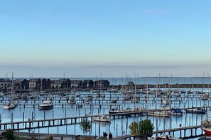 A marina with numerous boats docked at piers, a clear sky, and buildings in the background. - Sea view villa no. 15 (Großenbrode)