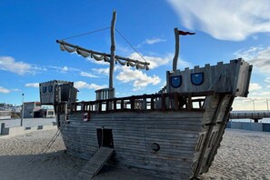 A wooden ship structure with a lifebuoy, a flag, and a small door. - Sea view villa no. 15 (Großenbrode)