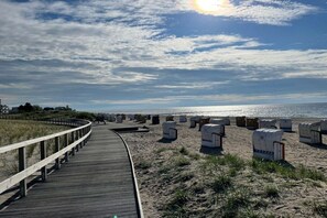 A wooden boardwalk leading to a beach with beach chairs and a clear sky. - Sea view villa no. 15 (Großenbrode)